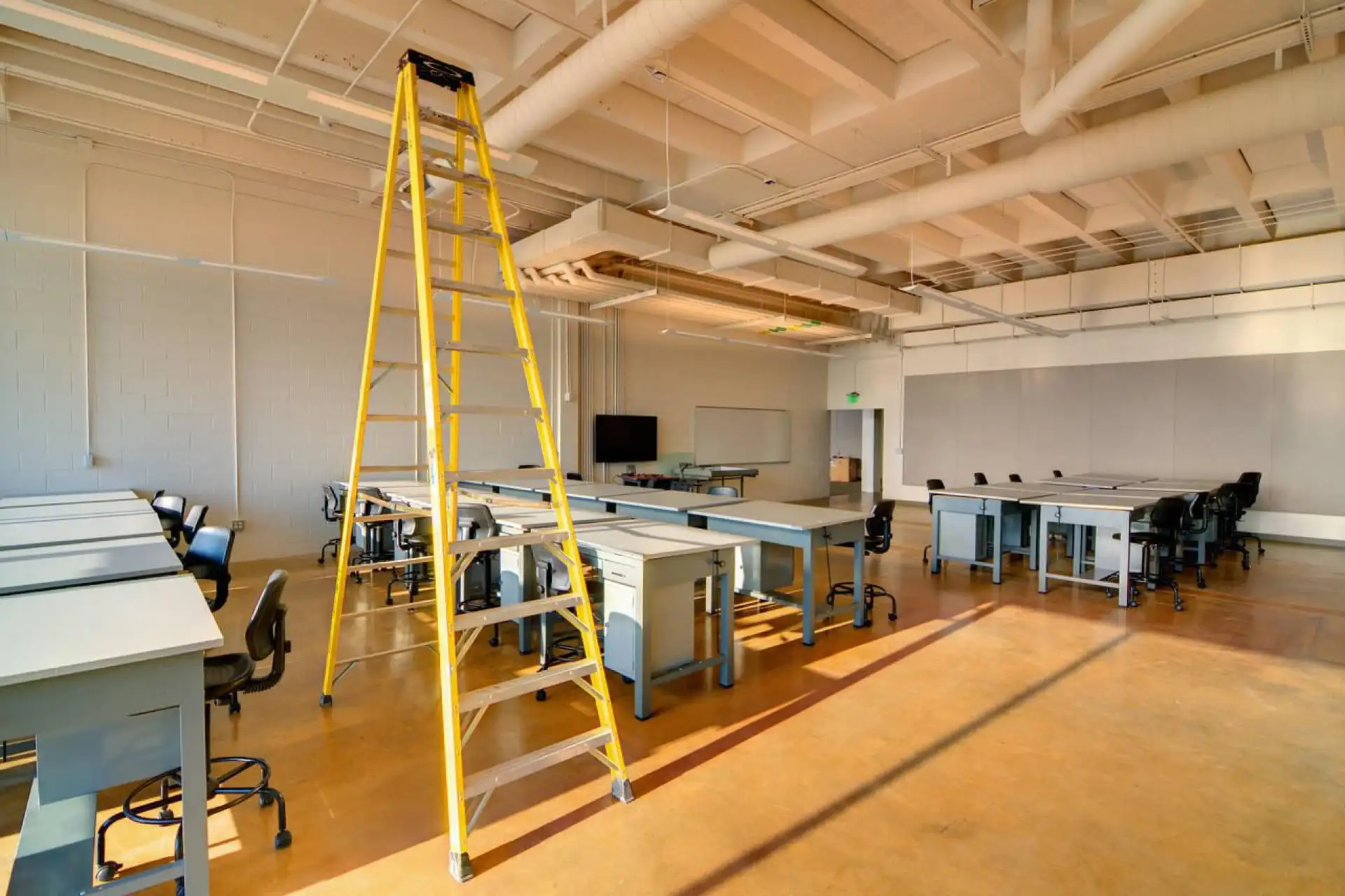 Intérieur de bureau en cours de rénovation avec une échelle jaune et des tables