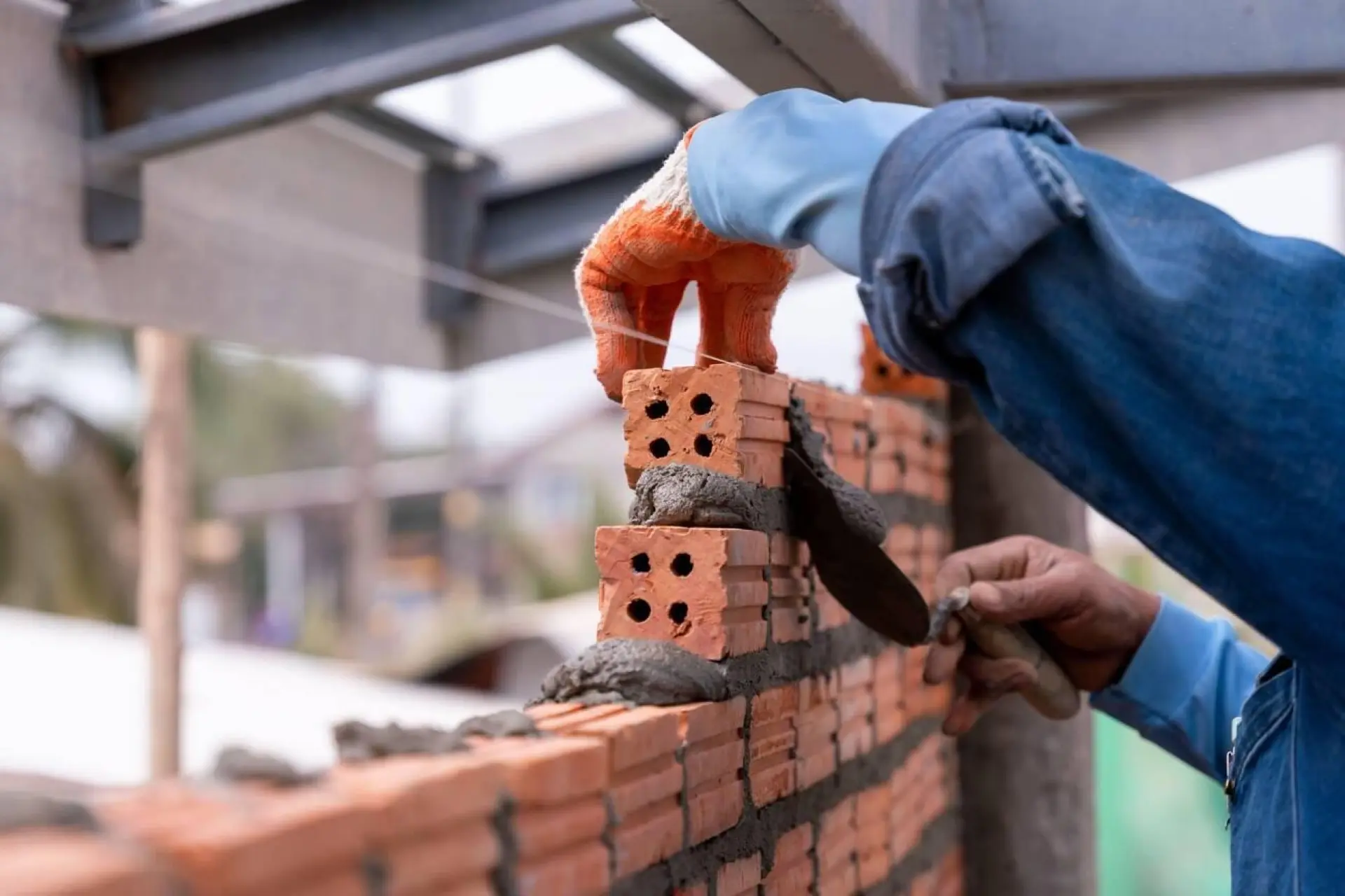 Un artisan maçon en train de construire un mur en briques rouges, mettant en place chaque brique avec soin.