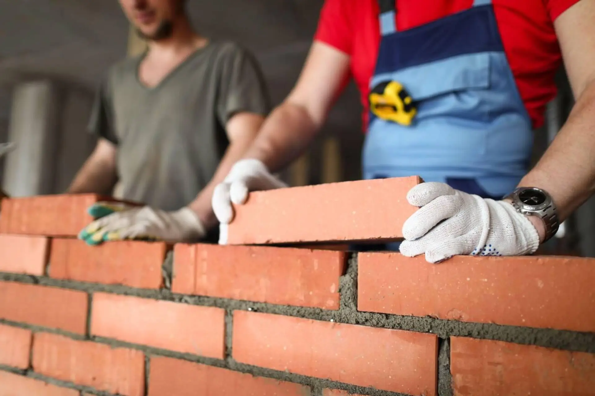 Deux maçons travaillant ensemble pour poser des briques rouges sur un nouveau mur.